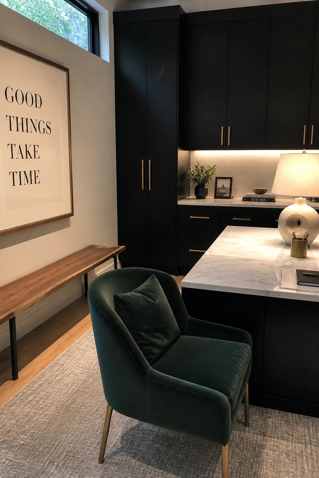 Modern dark green velvet chair beside black cabinets, marble island, and inspirational wall art