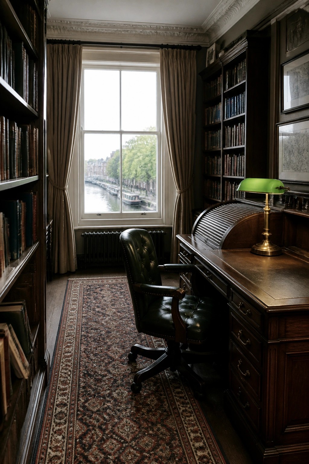 Elegant study with dark wooden desk, green lamp, leather chair, and canal view.