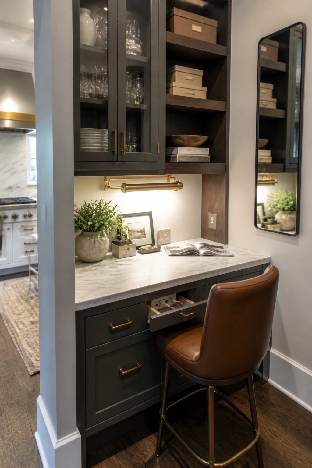 A built-in workspace with a marble countertop, dark gray cabinetry, open upper shelves, a brown leather stool, and a pull-out drawer showing electrical outlets.