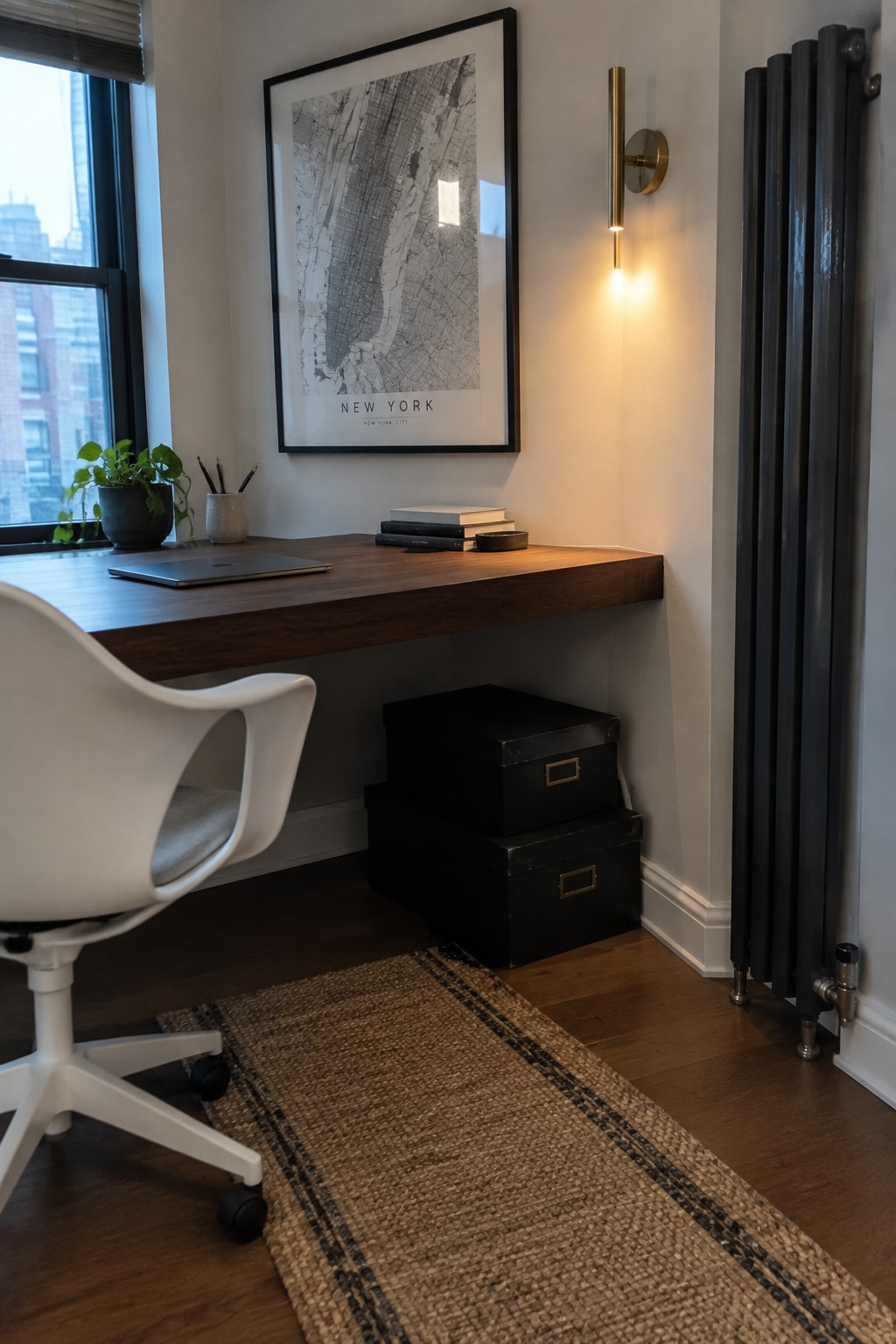 A compact home office with a wall-mounted wooden desk, black storage boxes beneath it, a white office chair, and a framed map print above the desk.