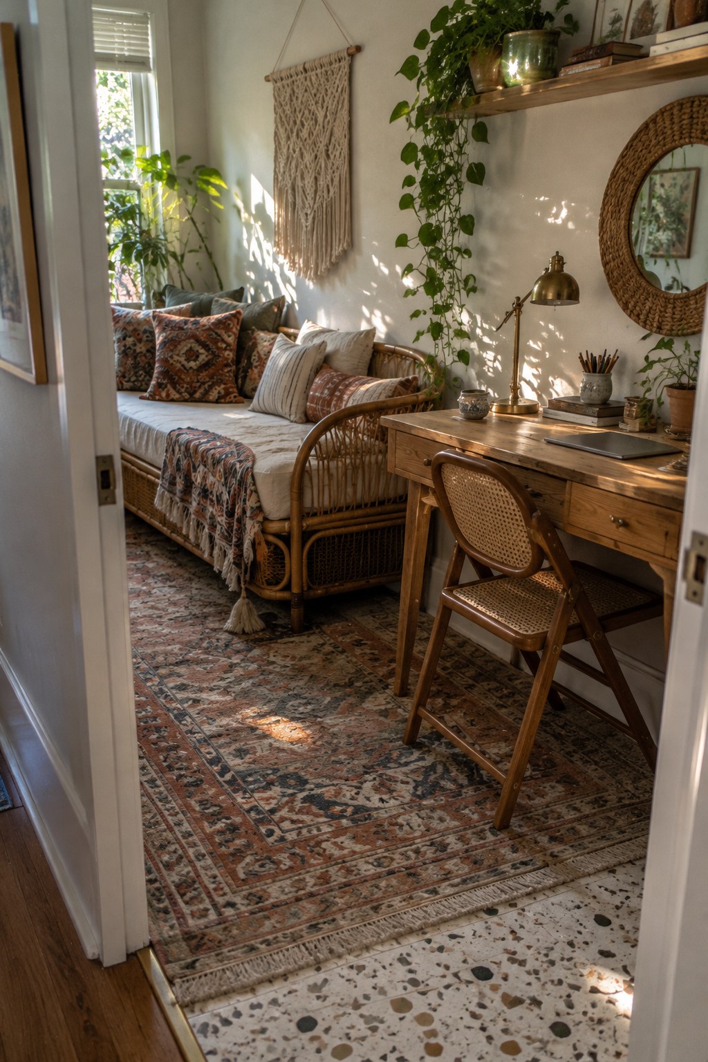 Sunlit bohemian nook with rattan daybed, wooden desk, patterned rug, and lush plants.