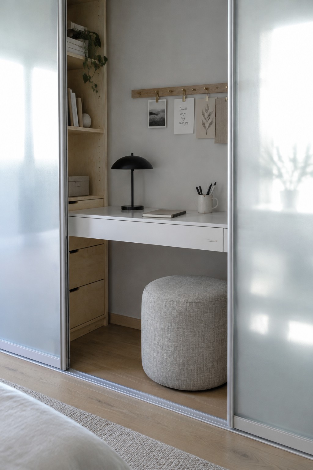 Minimalist white desk in alcove with black lamp, gray ottoman, shelves and wall clips