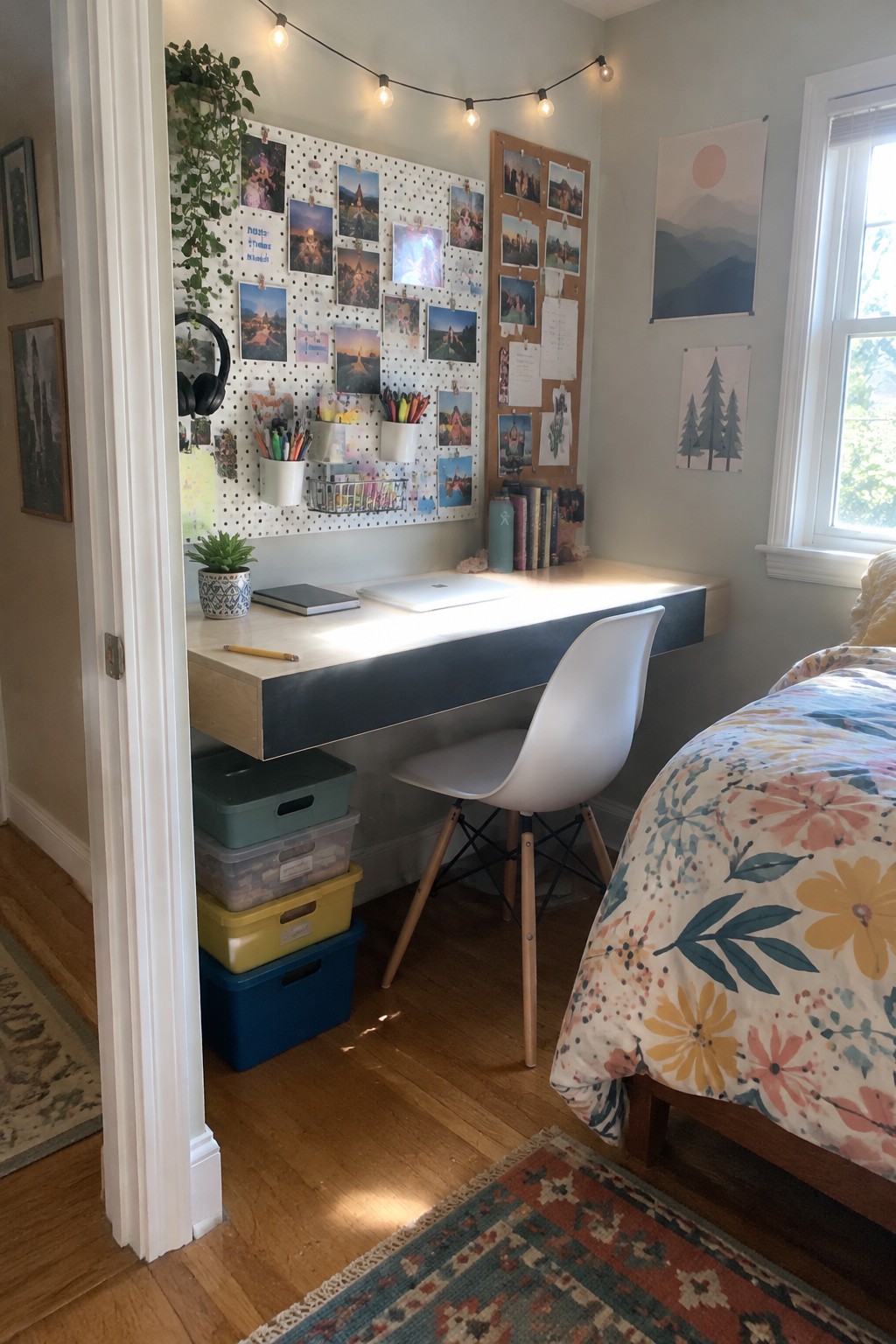 A bedroom corner featuring a floating wood desk with colorful storage bins stacked underneath, a white chair, a pegboard on the wall above, and a bed visible to the right.
